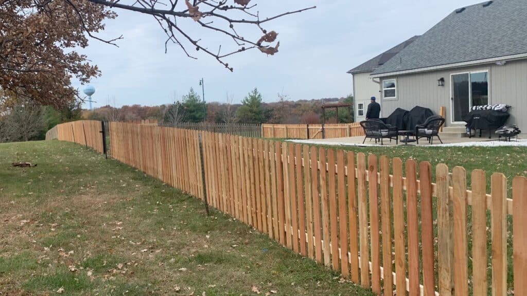 Newly installed cedar picket fence bordering a residential property.