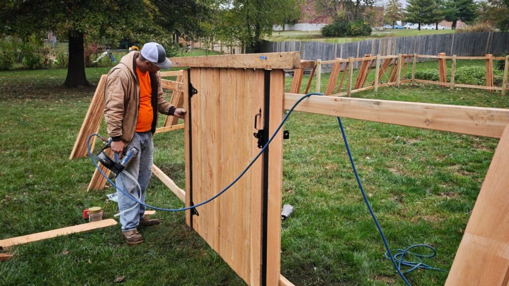 Professional contractor building a custom wood privacy fence gate during a residential fence replacement project.