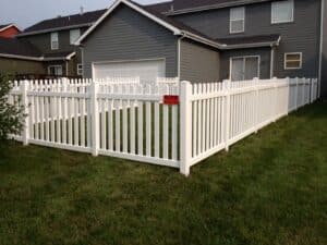White vinyl dog-ear picket fence enclosing a backyard lawn.