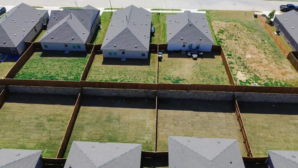 Aerial view of adjacent residential backyards with wood privacy fencing dividing surveyed property lines.